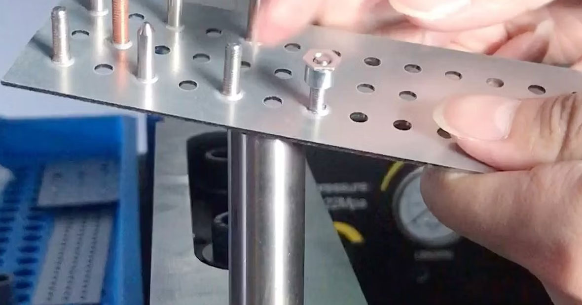 Technicien inspectant la fixation d'une protection de pied de rayonnage jaune dans un entrepôt industriel